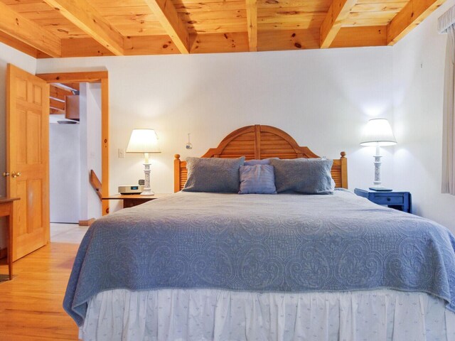 bedroom with beamed ceiling, light wood finished floors, and wood ceiling