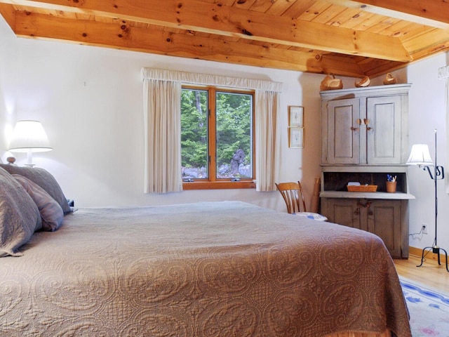 bedroom featuring beam ceiling, wooden ceiling, and light wood-style flooring