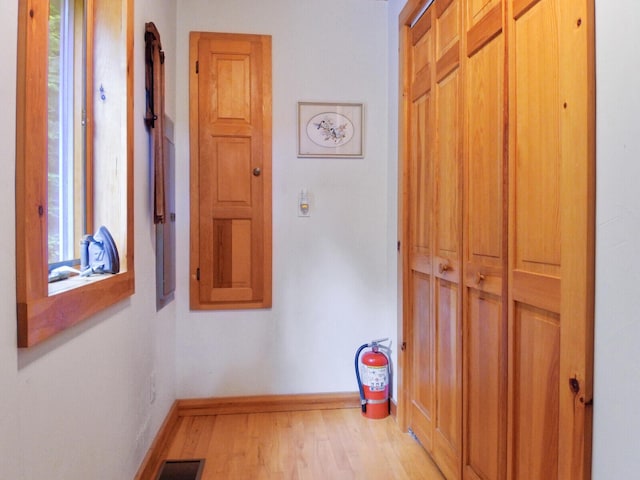 hall featuring visible vents, light wood-style flooring, and baseboards