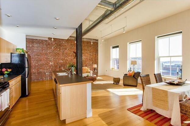 15 Brown St Unit 205, Portland, ME 04101 - kitchen with light wood finished floors, gas range oven, brick wall, dark countertops, and plenty of natural light