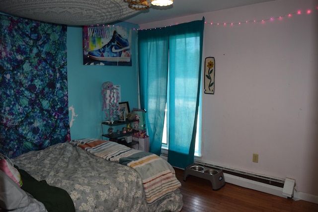 bedroom with multiple windows, a baseboard heating unit, and hardwood / wood-style floors