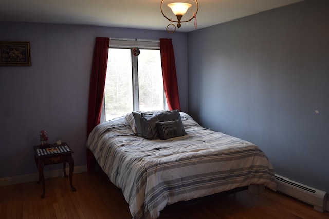 bedroom with baseboards, a baseboard radiator, and wood finished floors