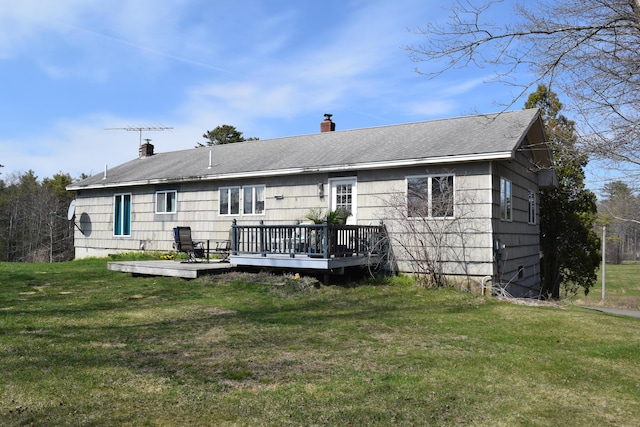 rear view of property with a lawn, a deck, and a chimney