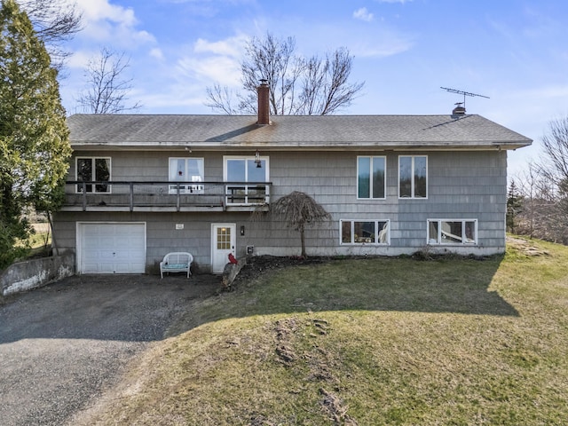rear view of property with roof with shingles, a garage, a chimney, a lawn, and driveway