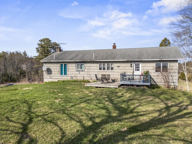rear view of house featuring a chimney, a lawn, and a deck