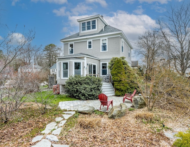 back of house with a shingled roof and a patio area