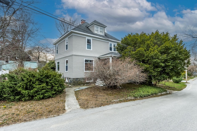 view of front of house featuring a chimney and roof with shingles