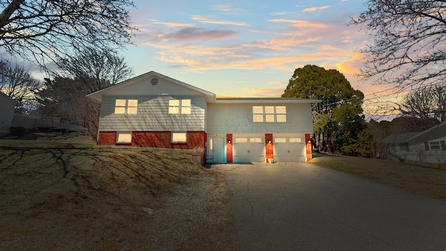 tri-level home featuring a garage, driveway, and brick siding