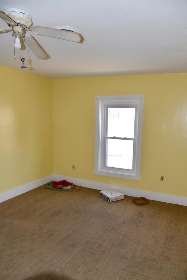 carpeted spare room with baseboards and ceiling fan
