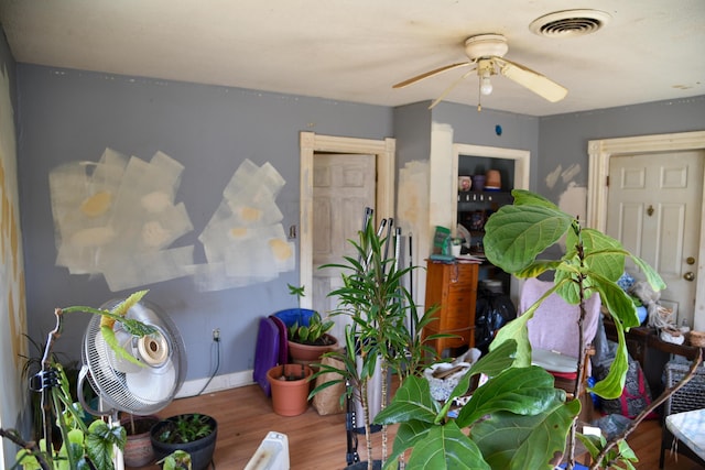 interior space with wood finished floors, visible vents, baseboards, and ceiling fan