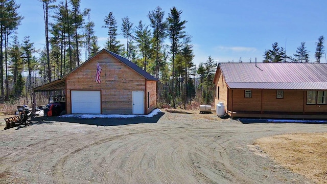476 N Rd, Medford, ME 04463 - view of property exterior featuring dirt driveway, metal roof, an outdoor structure, and a garage