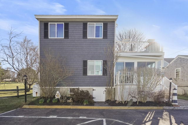 view of front of property with uncovered parking, fence, and a balcony