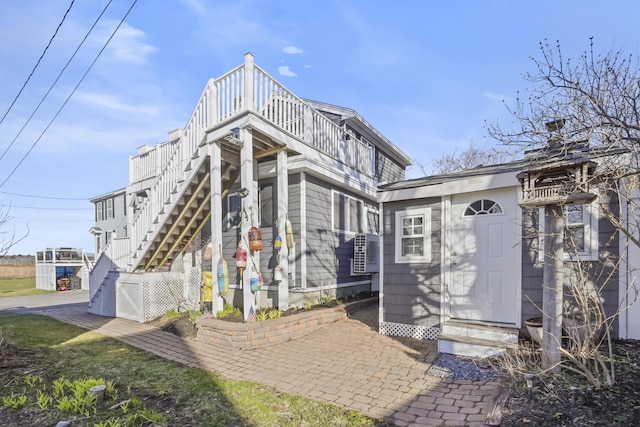 rear view of property featuring entry steps, stairs, and a balcony
