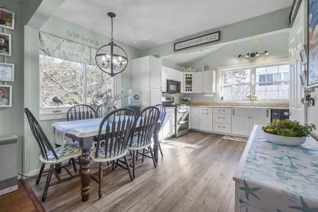dining space with light wood-style flooring, beverage cooler, lofted ceiling, and a notable chandelier