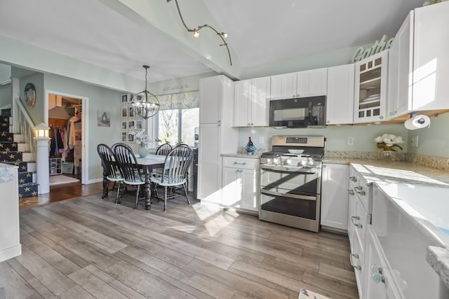 kitchen with black microwave, white cabinetry, range with two ovens, and light wood-style floors