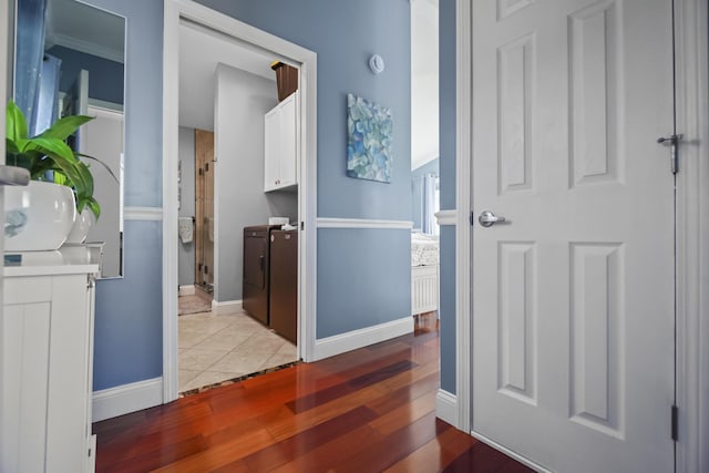 corridor featuring baseboards, washer and dryer, and light tile patterned flooring