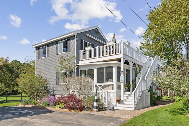 17 Clifford Ln, Wells, ME 04090 - view of front of house featuring stairs, a balcony, a sunroom, and uncovered parking
