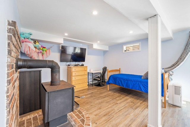 bedroom featuring wood finished floors, recessed lighting, and a wood stove