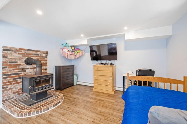 bedroom featuring recessed lighting, wood finished floors, a wood stove, and baseboard heating