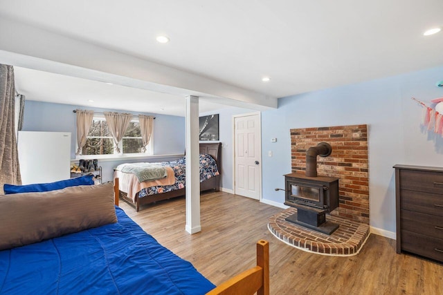bedroom featuring baseboards, a wood stove, wood finished floors, and recessed lighting