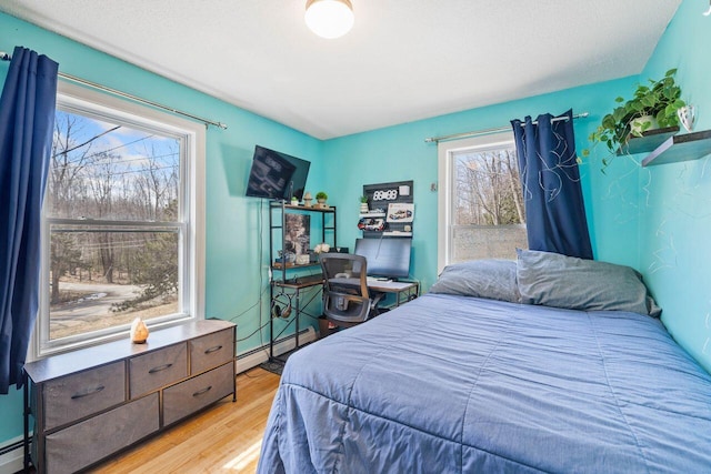 bedroom featuring a baseboard radiator, light wood-style flooring, and baseboard heating