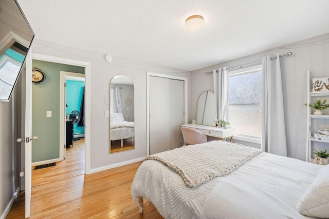 bedroom featuring visible vents, multiple windows, light wood finished floors, and a closet