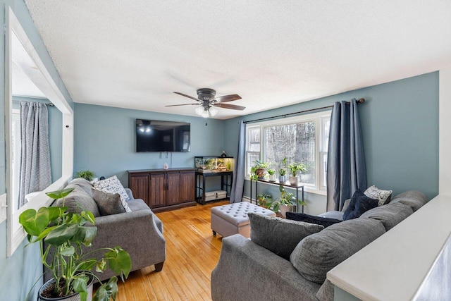 living room featuring a ceiling fan, a textured ceiling, and light wood-type flooring