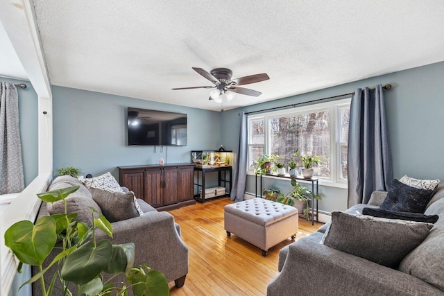 living room featuring a textured ceiling, light wood finished floors, baseboard heating, and ceiling fan