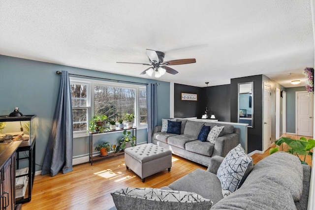 living room featuring a ceiling fan, wood finished floors, a textured ceiling, and baseboard heating