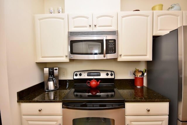 kitchen featuring dark stone countertops, cream cabinetry, and appliances with stainless steel finishes