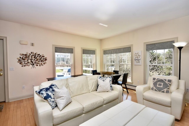 living room with a baseboard heating unit and light wood-style flooring
