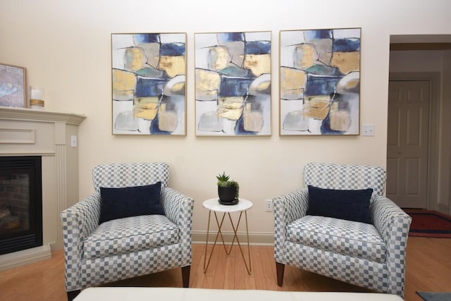 sitting room featuring baseboards, wood finished floors, and a fireplace