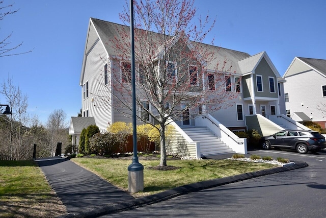 view of front of home with stairs and a front yard