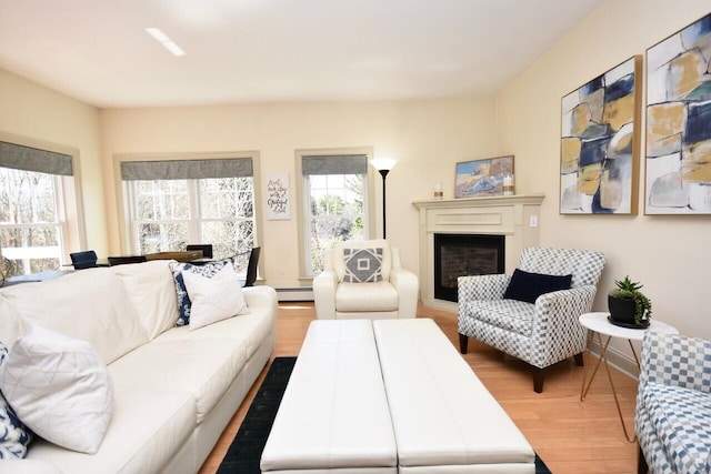living room featuring a glass covered fireplace, baseboard heating, and wood finished floors