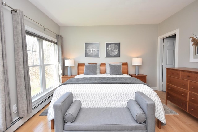bedroom with baseboard heating, multiple windows, and light wood-style flooring