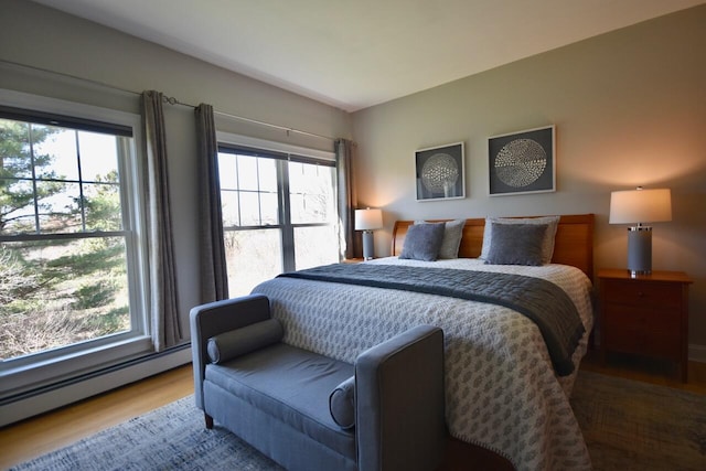 bedroom featuring wood finished floors, a baseboard radiator, and multiple windows
