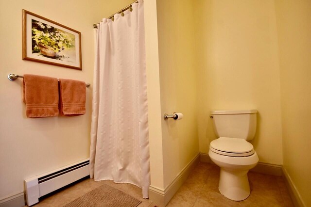 full bath with tile patterned floors, toilet, baseboards, a shower with shower curtain, and a baseboard radiator