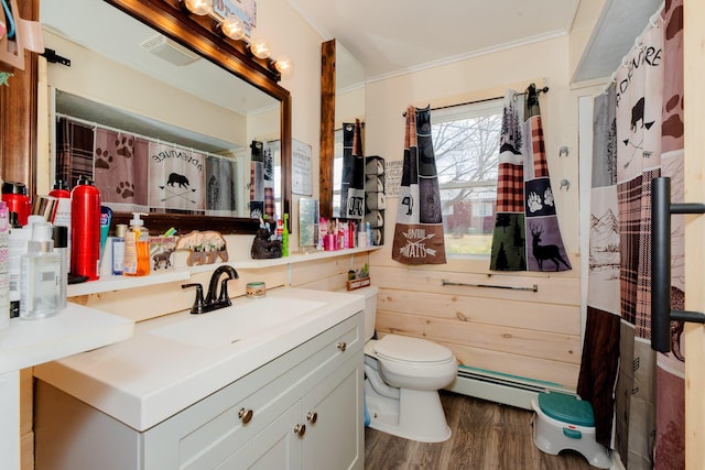 44 Sunset Ave, Wilton, ME 04294 - bathroom featuring crown molding, a baseboard heating unit, toilet, wood finished floors, and vanity