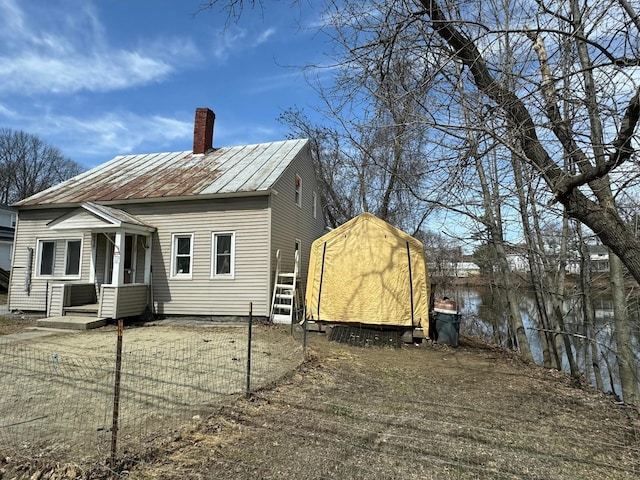 rear view of property with a standing seam roof, a chimney, metal roof, a storage shed, and an outdoor structure