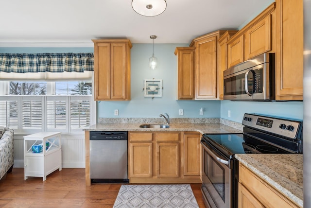 35 Barefoot Cottage Rd Unit 163, Wells, ME 04090 - kitchen with stainless steel appliances, light wood-style flooring, a sink, light stone counters, and hanging light fixtures