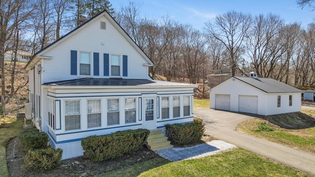 view of front of property featuring metal roof, an outbuilding, a chimney, and a detached garage