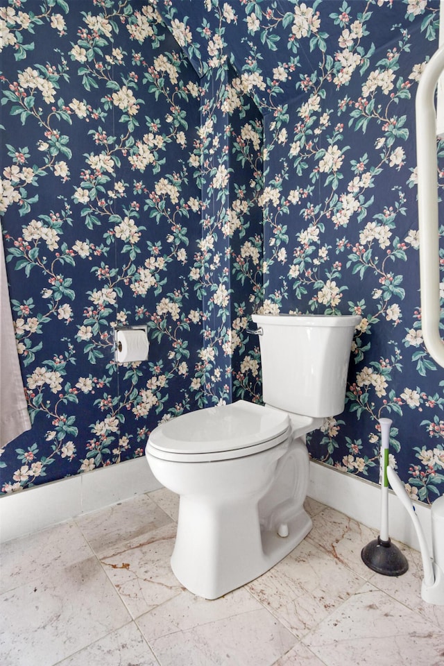 half bath featuring baseboards, toilet, and wallpapered walls