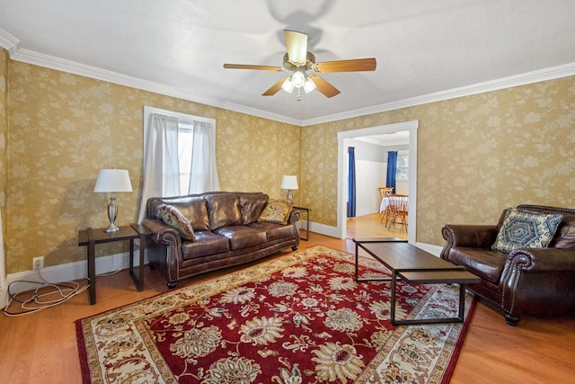 living area featuring crown molding, ceiling fan, baseboards, and wood finished floors