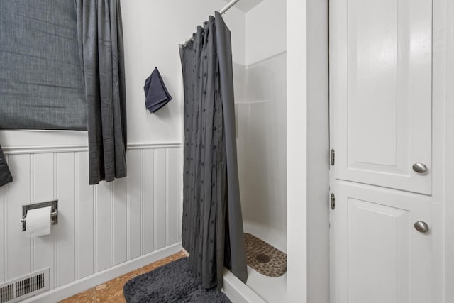 bathroom with wainscoting, a stall shower, and visible vents