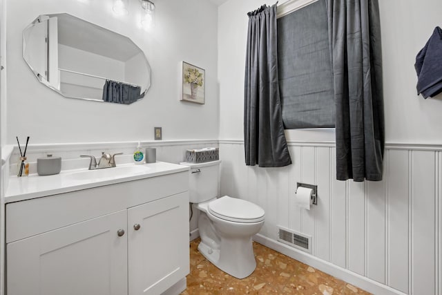bathroom with visible vents, wainscoting, toilet, and vanity