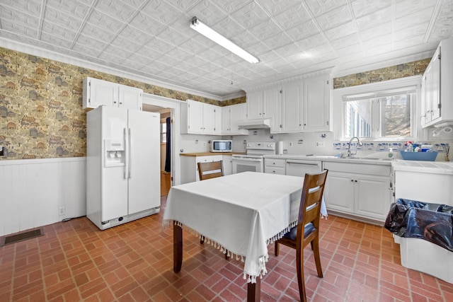 dining room featuring a wainscoted wall, an ornate ceiling, and brick patterned floor