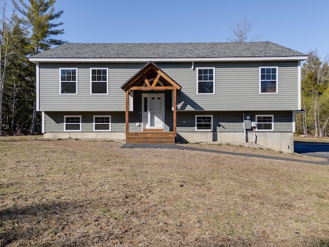 split foyer home with a front lawn and roof with shingles