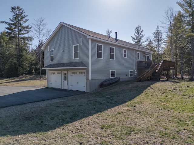 view of side of home featuring stairway, driveway, an attached garage, a yard, and a wooden deck