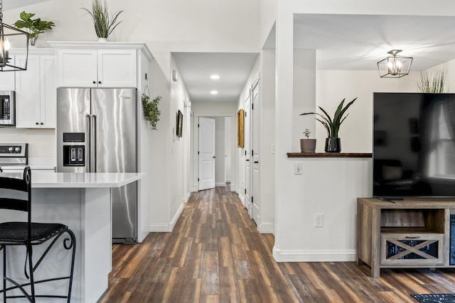 kitchen with a kitchen breakfast bar, dark wood-style floors, baseboards, light countertops, and appliances with stainless steel finishes