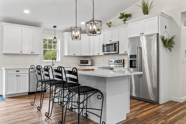 kitchen featuring white cabinets, stainless steel appliances, light countertops, a chandelier, and a kitchen bar